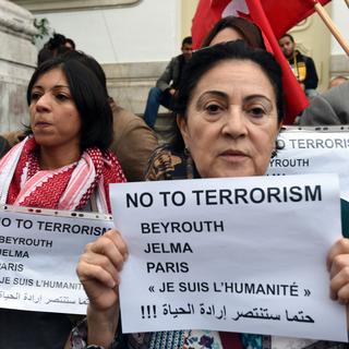 Une Tunisienne montre une affiche contre le terrorisme au cours d'une marche silencieuse à Tunis. [AFP - Fethi Belaid]