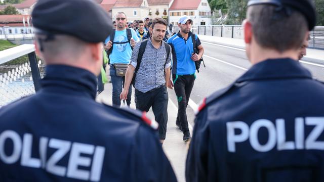 Un policier autrichien et son collègue hongrois à la frontière entre leurs deux pays. [AFP - Jure Makovec]