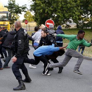 Des migrants échappent à la police alors qu'ils tentaient d'attraper un train pour l'Angleterre. Calais, France, le 30 juillet 2015. [EPA/Keystone - Yoan Valat]