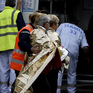 Les services de secours avec des passagers du car vendredi sur les lieux de la collision, à Puisseguin, dans le département français de la Gironde. [AFP - Jean-Pierre Muller]