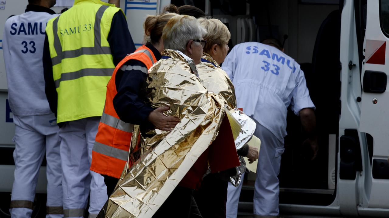 Les services de secours avec des passagers du car vendredi sur les lieux de la collision, à Puisseguin, dans le département français de la Gironde. [AFP - Jean-Pierre Muller]