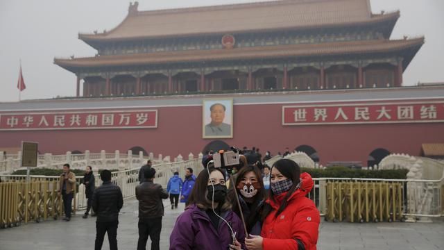 Des femmes équipées de masques respiratoires se prennent en photo sur la place Tiananmen, mardi 8 décembre 2015.