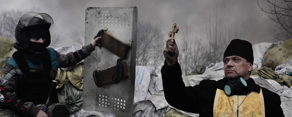 Un prêtre orthodoxe bénit des protestataire sur les barricades à Kiev, en Ukraine, le 20 février 2014. [DR - JEROME SESSINI]