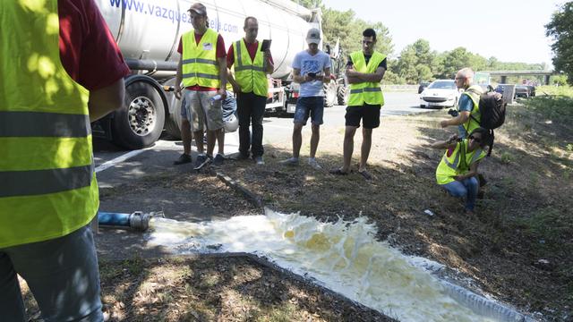 Des agriculteurs en colère déversant des litres de lait. [Citizenside/AFP - Céline Cazenave]