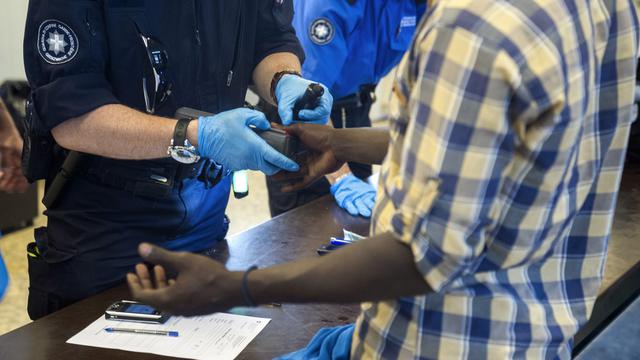 Un requérant d'asile se soumet à un contrôle d'identité à la gare de Chiasso le 16 juin. [TI-PRESS/Benedetto Galli]