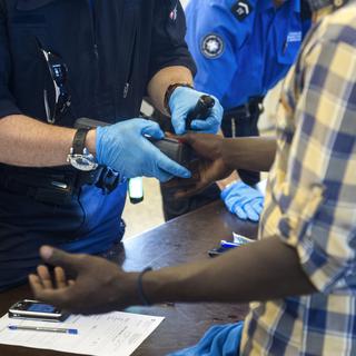 Un requérant d'asile se soumet à un contrôle d'identité à la gare de Chiasso le 16 juin. [TI-PRESS/Benedetto Galli]