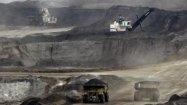 D'immenses camions transportent les sables bitumineux de la mine à l'extracteur (Pour avoir une idée de la taille de l'engin, on devine un ouvrier en orange montant à sa cabine). [AP/Keystone - Jeff McIntosh]