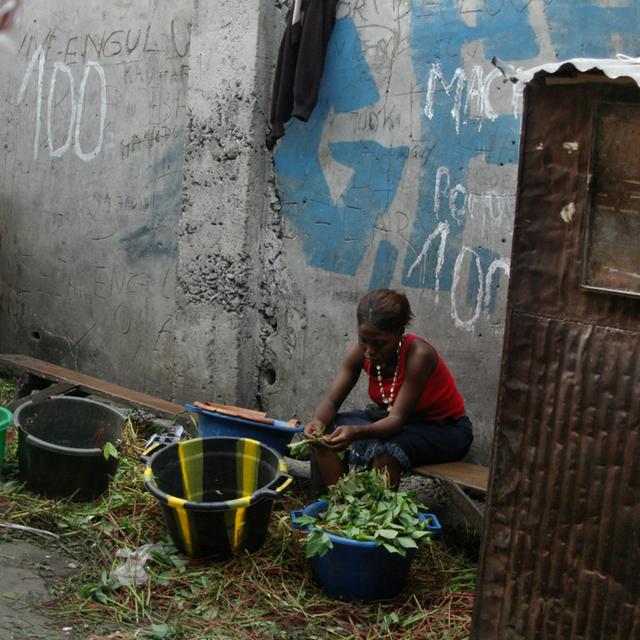 Une femme prépare un repas devant sa maison à Kinshasa, en RDC. [John Bompengo]