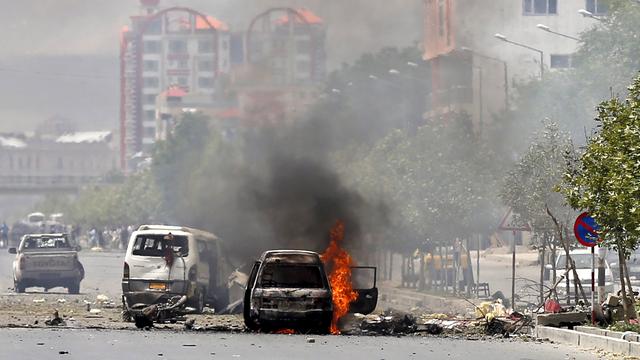 Un véhicule en feu après une explosion devant le Parlement afghan. [Keystone - Mohammad Ismail]