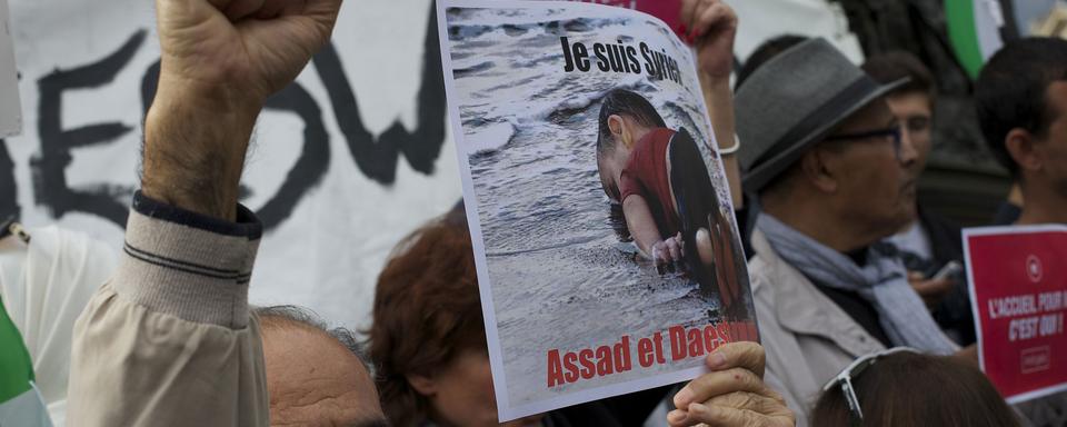 Un manifestant qui soutient les migrants brandit une pancarte avec la photo du petit Aylan à Paris le 5 septembre 2015. [CITIZENSIDE/AFP - Patrice Pierrot]