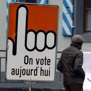 Une personne passe à côté d'un panneau "On vote aujourd'hui", samedi 29 novembre 2014 à Bex. [KEYSTONE/Laurent Gillieron]