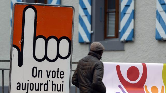 Une personne passe à côté d'un panneau "On vote aujourd'hui", samedi 29 novembre 2014 à Bex. [KEYSTONE/Laurent Gillieron]