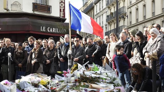 Les badauds observent une minute de silence devant Le Carillon, un des théâtres des fusillades de vendredi soir. [Eric Feferberg]