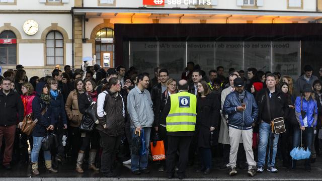 Des pendulaires attendent les bus de remplacement en gare d'Yverdon-les-Bains. [Keystone - Jean-Christophe Bott]