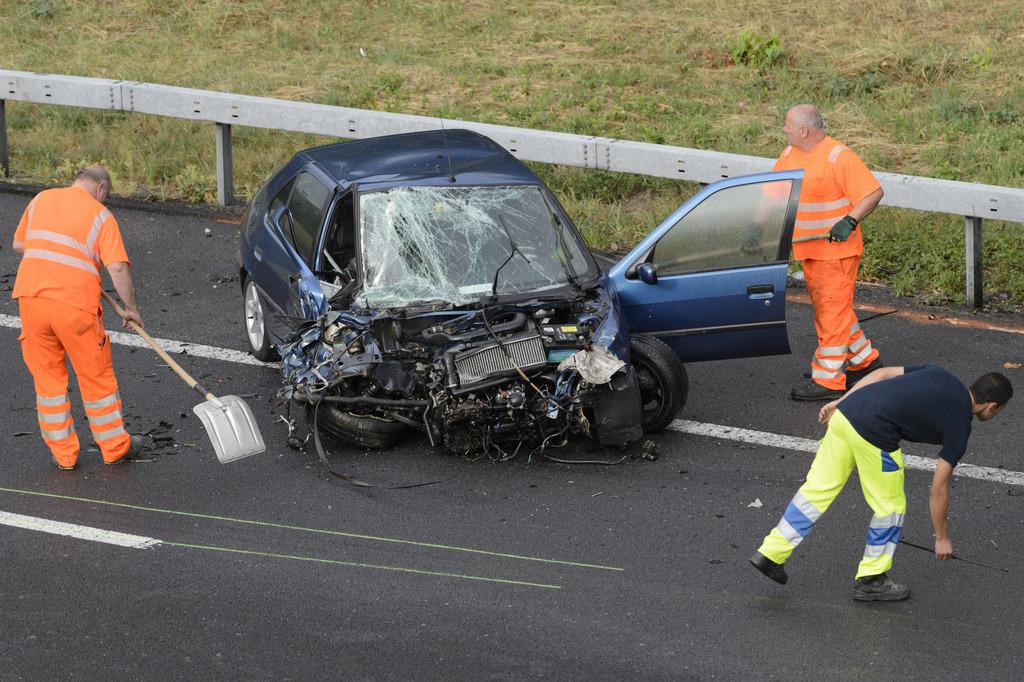 Des personnes remettent en état l'autoroute A1 après un accident survenu le 23 juillet 2015 à Cossonay (VD). [Keystone - Laurent Gilliéron]