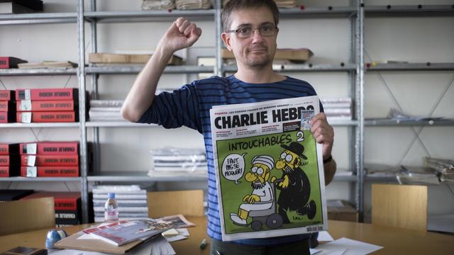 Le caricaturiste Charb, directeur de la rédaction de Charlie Hebdo, brandit le journal satirique titré "Intouchables 2" contenant plusieurs caricatures du prophète Mahomet après qu'un film américain provoque des émeutes dans le monde musulman. [Fred Dufour]