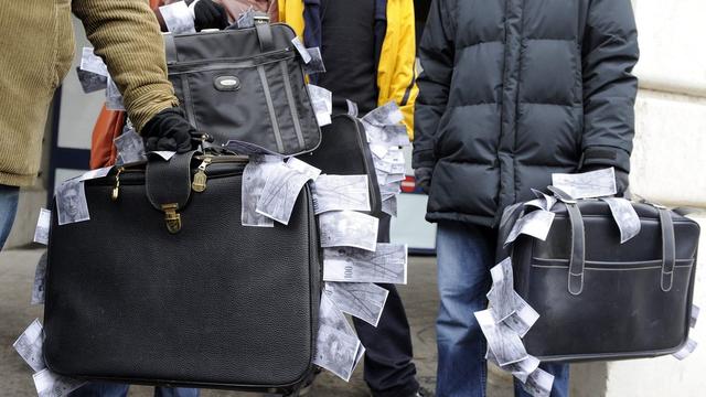 Valises de (faux) billets de banque suisses lors d'une manifestation à Lausanne en 2009. [DOMINIC FAVRE]