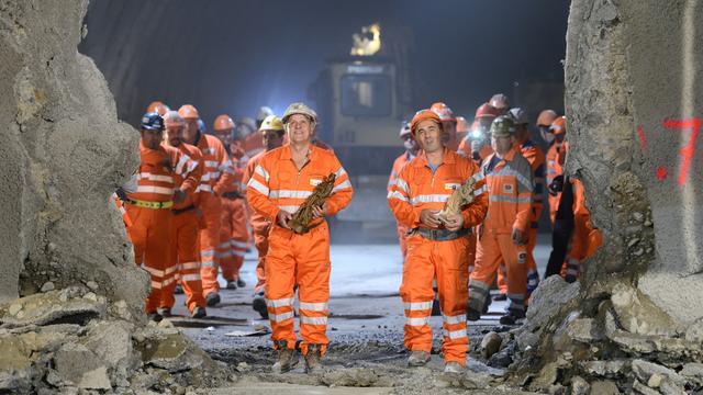 Des ouvriers portent des statuettes de Sainte-Barbe lors de la cérémonie marquant le percement du tunnel de Pinchat [KEYSTONE/Martial Trezzini]