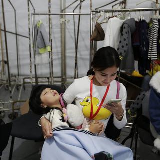 Mère chinoise et son enfant assoupi dans les bras. Les couples sont désormais autorisés à avoir un deuxième enfant. [EPA/Keystone - How Hwee Young]