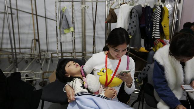 Mère chinoise et son enfant assoupi dans les bras. Les couples sont désormais autorisés à avoir un deuxième enfant. [EPA/Keystone - How Hwee Young]