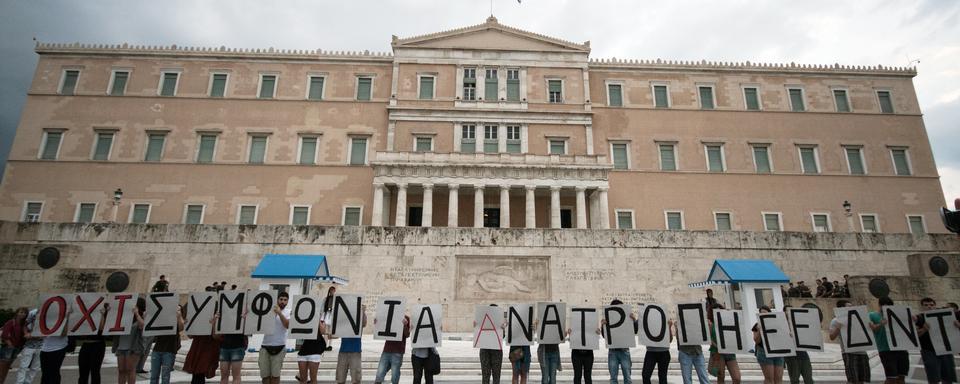 Devant le Parlement grec, de jeunes militants de gauche font campagne pour le non au référendum sur l'offre des créanciers à la Grèce, qui doit se tenir le dimanche 5 juillet. [DPA/Keystone - Socrates Baltagiannis]