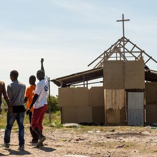 Des migrants devant une église de fortune à Calais. [AFP - Philippe Huguen]
