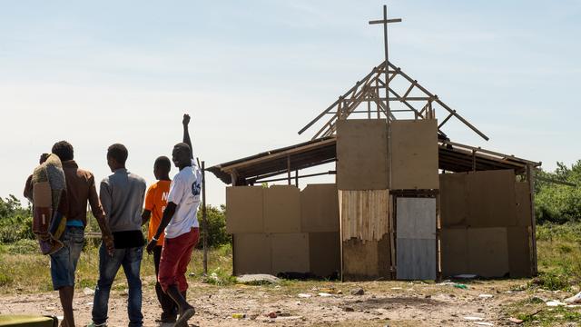 Des migrants devant une église de fortune à Calais. [AFP - Philippe Huguen]