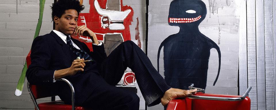 Le peintre Jean-Michel Basquiat et l'une de ses oeuvres en 1985. [Brooklyn Museum / Keystone - Lizzy Himmel]