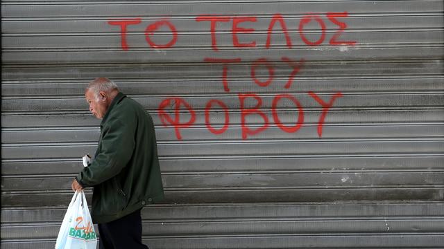 Un Grec passe devant un slogan qui clame "la fin de la peur" à Athènes. [NurPhoto/AFP - Panayiotis Tzamaros]