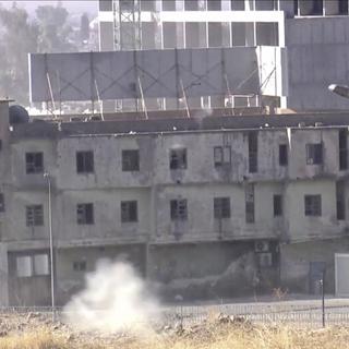 Un bâtiment de Kirkouk en proie à des combats. [Keystone - Rudaw TV via AP]