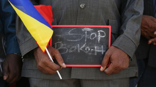 Un homme tient un écriteau avec l'inscription "Stop Boko Haram" et un drapeau du Tchad.