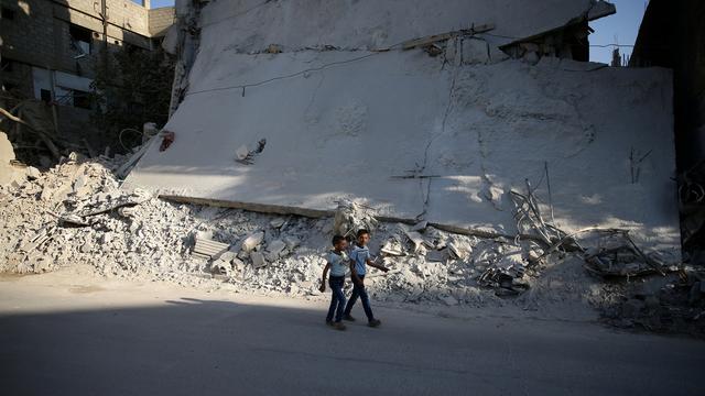 Des enfants passent devant un immeuble détruit à Douma, en banlieue de Damas. [Reuters - Bassam Khabieh]