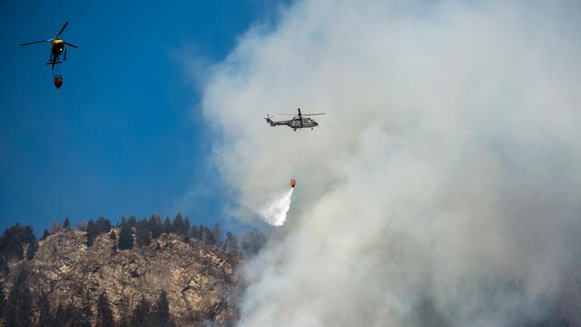 Les hélicoptères luttant contre les incendies aux Grisons cette semaine. [Keystone - Ti-Press/Gabriele Putzu]