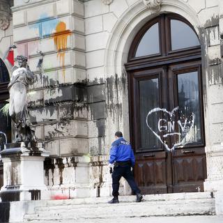 Un policier examine la façade du Grand Théâtre de Genève souillée de tags, 20.12.2015. [Keystone - Salvatore Di Nolfi]