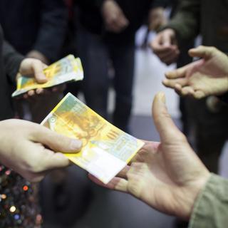 Les initiants au revenu inconditionnel de base ont distribué des billets de 10 francs en gare de Zurich pour lancer leur campagne. [Keystone - Ennio Leanza]