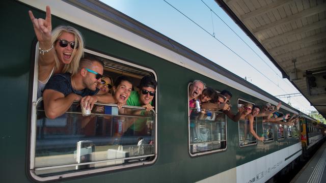 Le train est l'un des moyens de transport favori en Suisse, comme ici pour ces fêtards se rendant à la Street Parade de Lugano à Zurich le 13 août dernier. [KEYSTONE - Ti-Press/Davide Agosta]