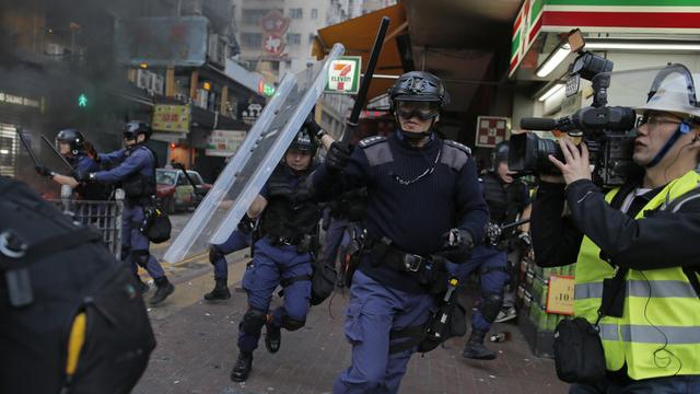 La police anti-émeute, visée par des projectiles en tous genres, passe à l'attaque, ce 9 février 2016, à Hong Kong.