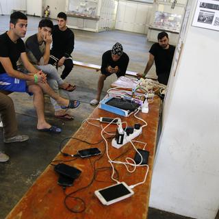 Des réfugiés rechargent leurs téléphones portables dans une structure d'accueil de Berlin, en Allemagne. [Reuters - Fabrizio Bensch]