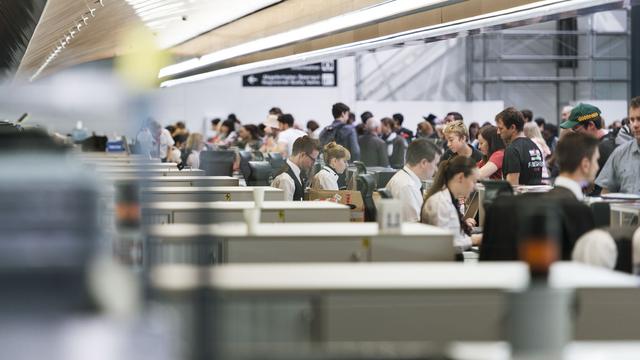 Des passagers et des employés dans le hall d'enregistrement de l'aéroport de Zurich. [Keystone - Christian Beutler]