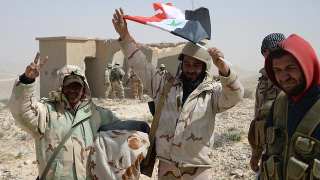 Des combattants de l'armée syrienne agitant le drapeau à l'entrée de la ville de Palmyre. [Mikhail Voskresenskiy / RIA Novosti]