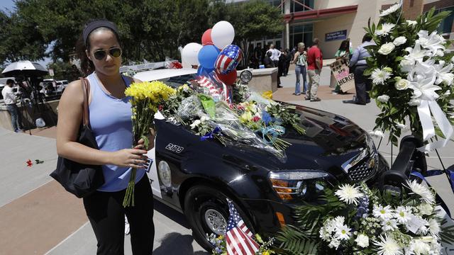 Une femme dépose des fleurs près d'un mémorial dédié aux policiers tués jeudi soir. [Eric Gay]