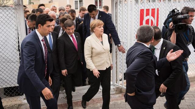 Angela Merkel, en compagnie du Premier ministre turc, a visité un camp de réfugiés. [German Federal Government/ Keystone - Steffen Kugler]