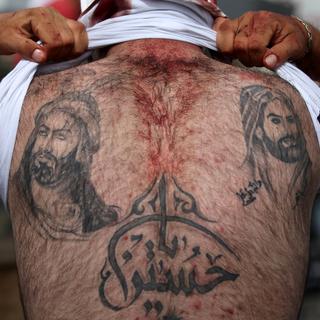 Un musulman chiite montre ses tatouages représentant les imams Ali et Hussein. [Alia Haju]