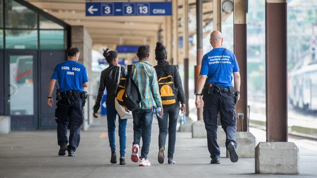 Un garde-frontière accompagne de jeunes réfugiés à la gare de Chiasso (TI). [Ti-Press/Keystone - Francesca Agosta]