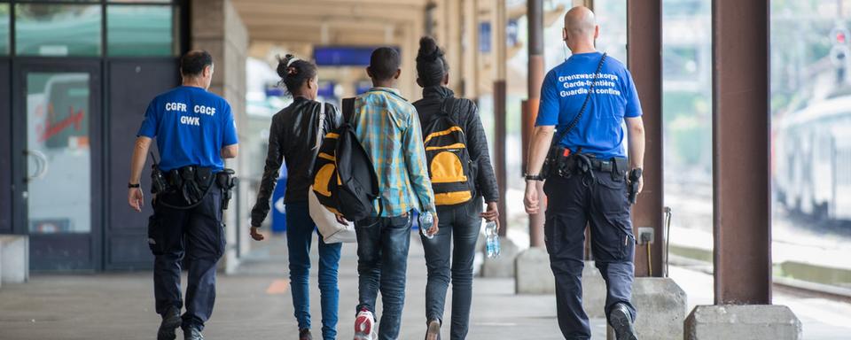 Un garde-frontière accompagne de jeunes réfugiés à la gare de Chiasso (TI). [Ti-Press/Keystone - Francesca Agosta]