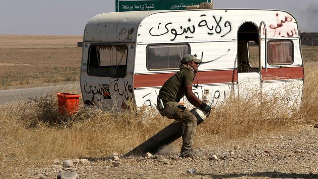 Un combattant irakien tente de désamorcer une mine terrestre posée par le groupe EI. [AFP - Safin Hamed]