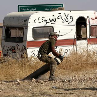 Un combattant irakien tente de désamorcer une mine terrestre posée par le groupe EI. [AFP - Safin Hamed]