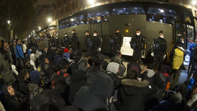 Des migrants afghans attendent devant la police durant l'évacuation d'un camp, à Paris. [Afp - Joel Saget]