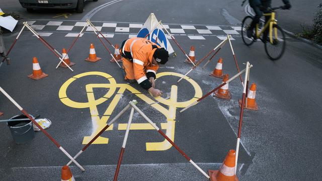 Lundi 28 novembre: un ouvrier termine le marquage de deux rues où les vélos auront la priorité sur les voitures à Zurich. Il s'agit d'un projet pilote initié par l'Office fédéral des routes (OFROU) auquel participent cinq villes alémaniques. [Keystone - Christian Beutler]