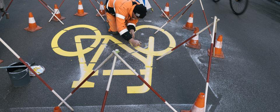 Lundi 28 novembre: un ouvrier termine le marquage de deux rues où les vélos auront la priorité sur les voitures à Zurich. Il s'agit d'un projet pilote initié par l'Office fédéral des routes (OFROU) auquel participent cinq villes alémaniques. [Keystone - Christian Beutler]